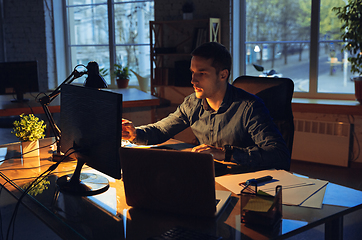 Image showing Man working in office alone during coronavirus or COVID-19 quarantine, staying to late night