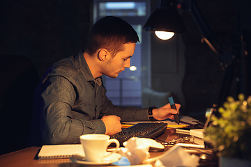 Image showing Man working in office alone during coronavirus or COVID-19 quarantine, staying to late night