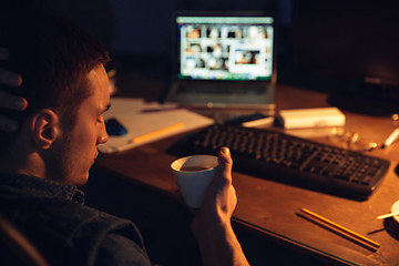 Image showing Man working in office alone during coronavirus or COVID-19 quarantine, staying to late night