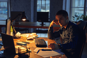 Image showing Man working in office alone during coronavirus or COVID-19 quarantine, staying to late night