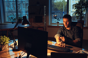 Image showing Man working in office alone during coronavirus or COVID-19 quarantine, staying to late night