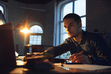 Image showing Man working in office alone during coronavirus or COVID-19 quarantine, staying to late night