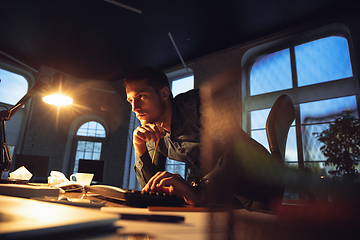 Image showing Man working in office alone during coronavirus or COVID-19 quarantine, staying to late night