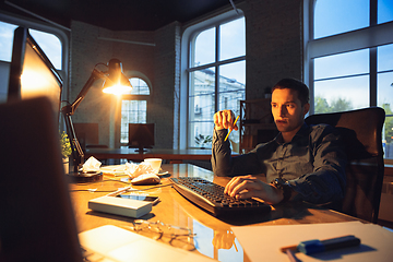 Image showing Man working in office alone during coronavirus or COVID-19 quarantine, staying to late night