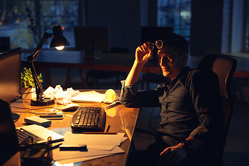 Image showing Man working in office alone during coronavirus or COVID-19 quarantine, staying to late night