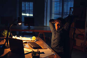 Image showing Man working in office alone during coronavirus or COVID-19 quarantine, staying to late night