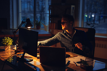 Image showing Man working in office alone during coronavirus or COVID-19 quarantine, staying to late night