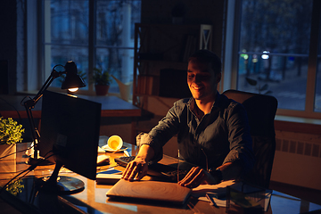 Image showing Man working in office alone during coronavirus or COVID-19 quarantine, staying to late night