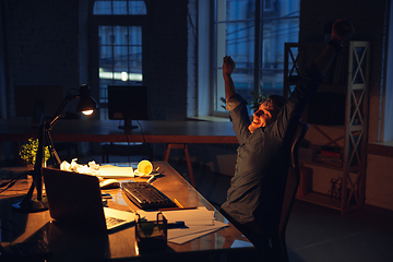 Image showing Man working in office alone during coronavirus or COVID-19 quarantine, staying to late night