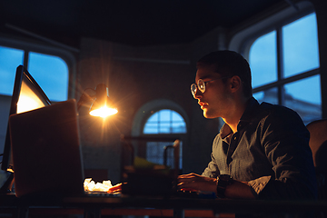 Image showing Man working in office alone during coronavirus or COVID-19 quarantine, staying to late night