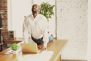 Image showing Young african-american man doing yoga at home while being quarantine and freelance working