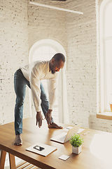 Image showing Young african-american man doing yoga at home while being quarantine and freelance working