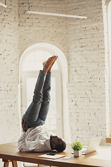 Image showing Young african-american man doing yoga at home while being quarantine and freelance working