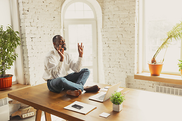 Image showing Young african-american man doing yoga at home while being quarantine and freelance working