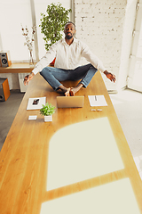 Image showing Young african-american man doing yoga at home while being quarantine and freelance working