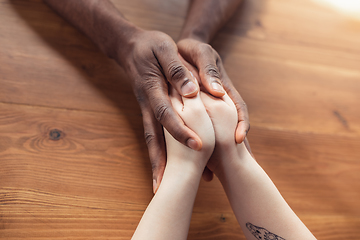 Image showing Close up of african-american male and caucasian female hands holding