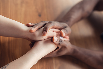 Image showing Close up of african-american male and caucasian female hands holding