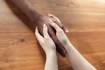 Image showing Close up of african-american male and caucasian female hands holding