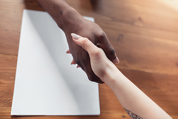 Image showing Close up of african-american male and caucasian female hands, working in office