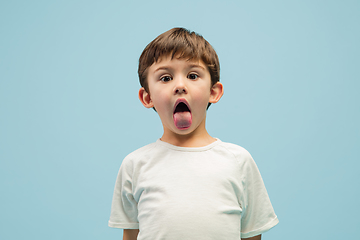 Image showing Happy caucasian little boy isolated on blue studio background. Looks happy, cheerful, sincere. Copyspace. Childhood, education, emotions concept