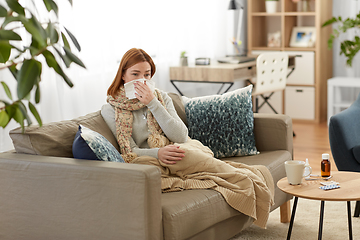 Image showing sick woman blowing nose in paper tissue at home