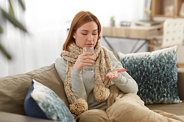 Image showing sick woman taking medicine with water at home