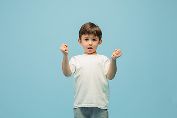 Image showing Happy caucasian little boy isolated on blue studio background. Looks happy, cheerful, sincere. Copyspace. Childhood, education, emotions concept