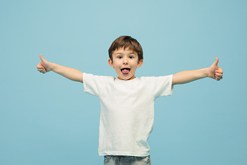 Image showing Happy caucasian little boy isolated on blue studio background. Looks happy, cheerful, sincere. Copyspace. Childhood, education, emotions concept