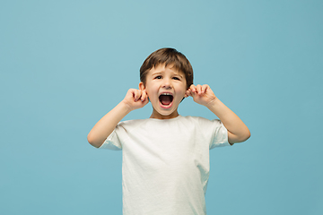 Image showing Happy caucasian little boy isolated on blue studio background. Looks happy, cheerful, sincere. Copyspace. Childhood, education, emotions concept