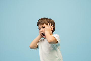 Image showing Happy caucasian little boy isolated on blue studio background. Looks happy, cheerful, sincere. Copyspace. Childhood, education, emotions concept