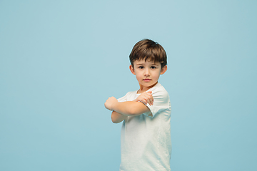 Image showing Happy caucasian little boy isolated on blue studio background. Looks happy, cheerful, sincere. Copyspace. Childhood, education, emotions concept