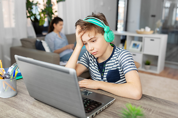 Image showing sad boy with laptop and headphones at home