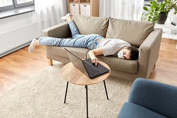 Image showing sick bored woman with laptop lying on sofa at home