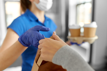 Image showing delivery girl in mask giving paper bag to woman