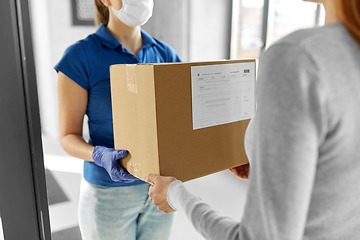 Image showing delivery girl in face mask giving parcel to woman