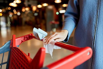 Image showing hand cleaning shopping cart handle with wet wipe