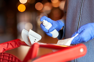 Image showing woman cleaning shopping cart handle with sanitizer