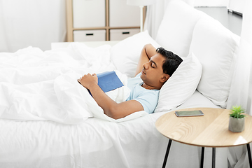 Image showing indian man with book sleeping in bed at home