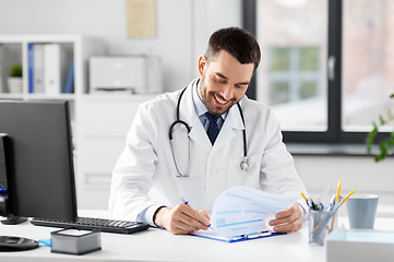 Image showing smiling male doctor with clipboard at hospital