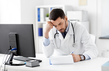 Image showing stressed male doctor with clipboard at hospital