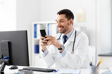 Image showing smiling male doctor with smartphone at hospital