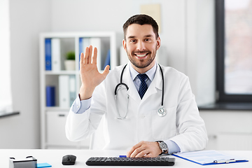 Image showing happy male doctor waving hand at hospital