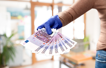 Image showing close up of hand in medical glove with money