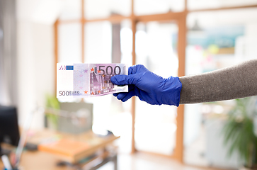 Image showing close up of hand in medical glove with money