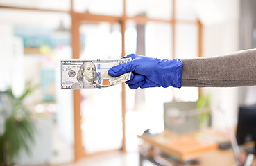 Image showing close up of hand in medical glove with money