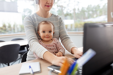 Image showing mother with baby working on laptop at home office