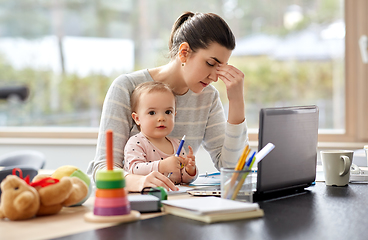 Image showing tired mother with baby working at home office