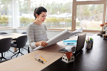 Image showing young woman with blueprint working at home office