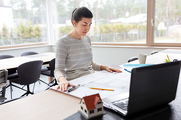 Image showing young woman with blueprint working at home office