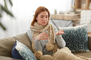 Image showing sick woman taking medicine with water at home